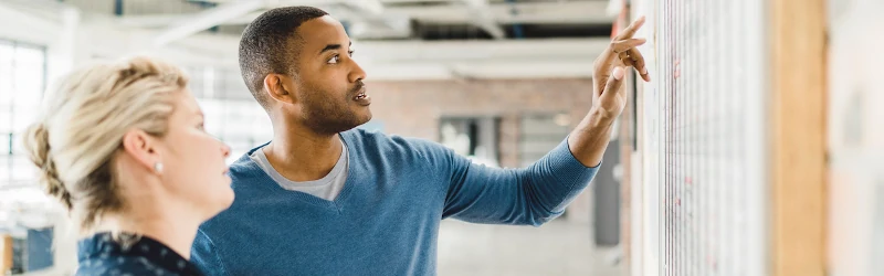 Two teacher leaders writing on a whiteboard