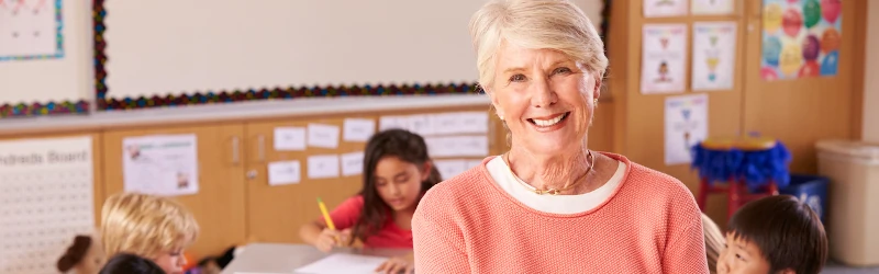 Early childhood education teacher with a student in the background